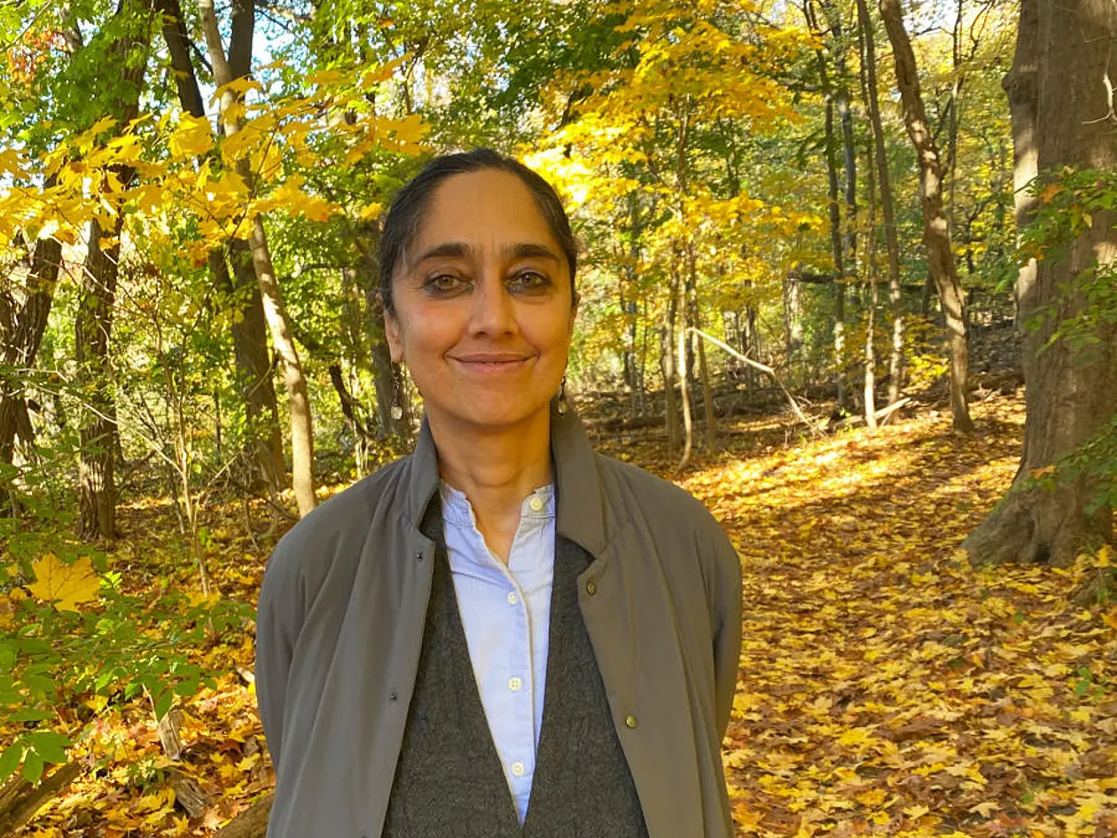 Foto von Professor Leela Gandhi, die in einem herbstlichen Wald steht