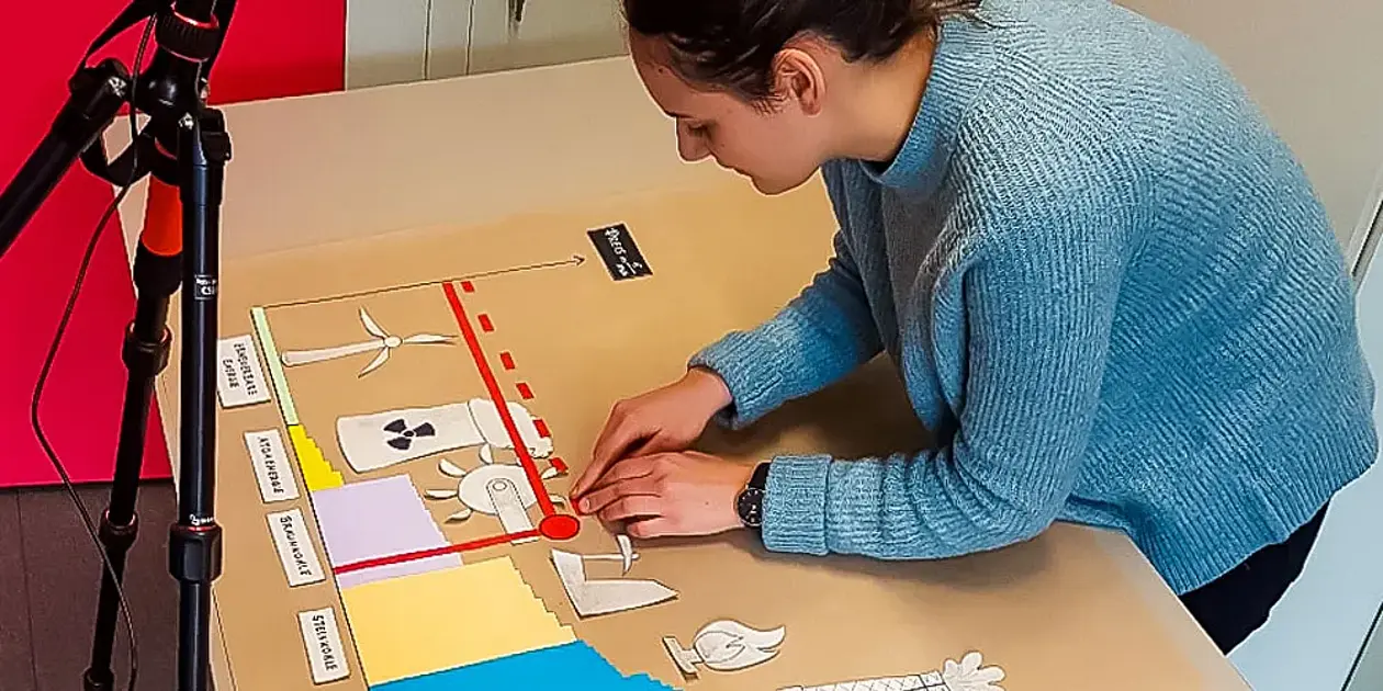 Eine Studentin erklärt eine Theorie aus der Energiewirtschaft mit einem Erklärvideo in Legetechnik.