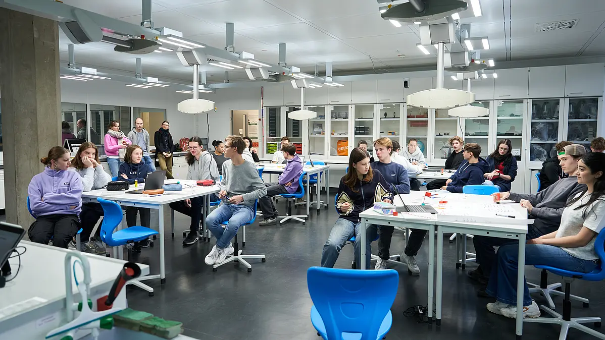 Eine Schulklasse sitzt im Tübinger MINT-Klassenzimmerraum an Tischen. TüMathLab