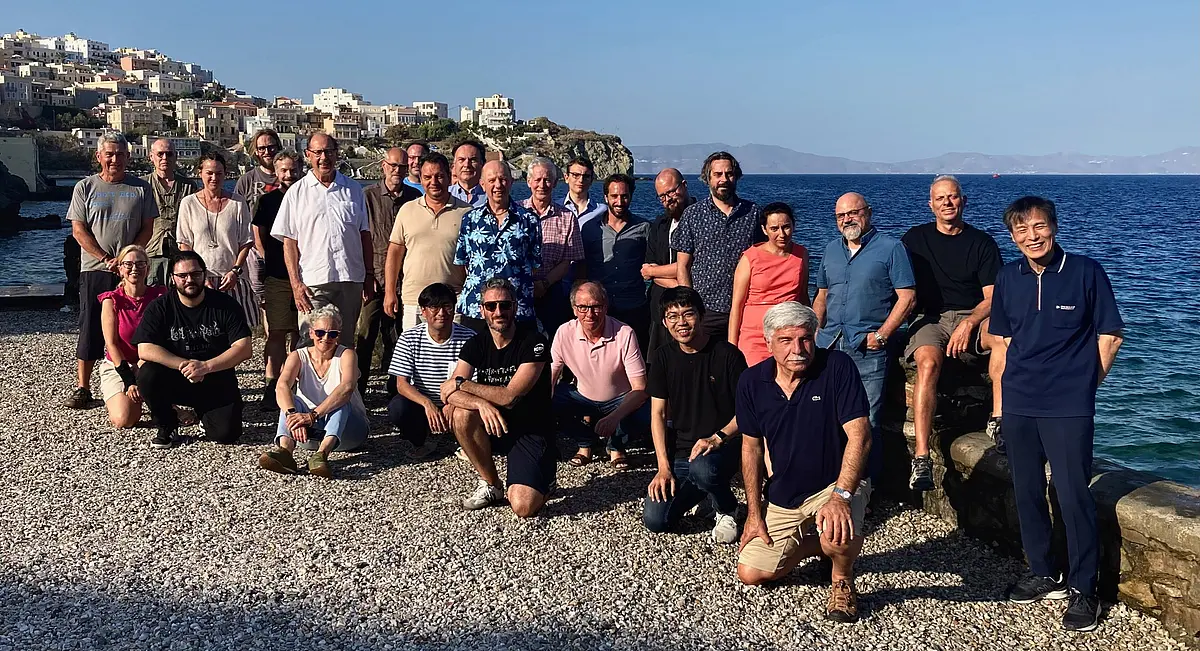 The symposium's participants stand in front of a beach scenery