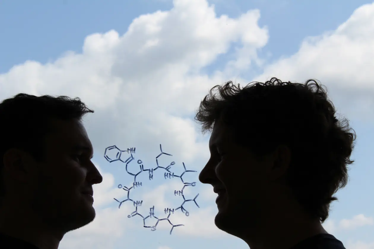 Die chemische Strukturformel des neu entdeckten Antibiotikums „Lugdunin“. Außerdem im Bild: die beiden Erstautoren Alexander Zipperer (links) und Martin Christoph Konnerth (rechts). Foto: Martin Christoph Konnerth