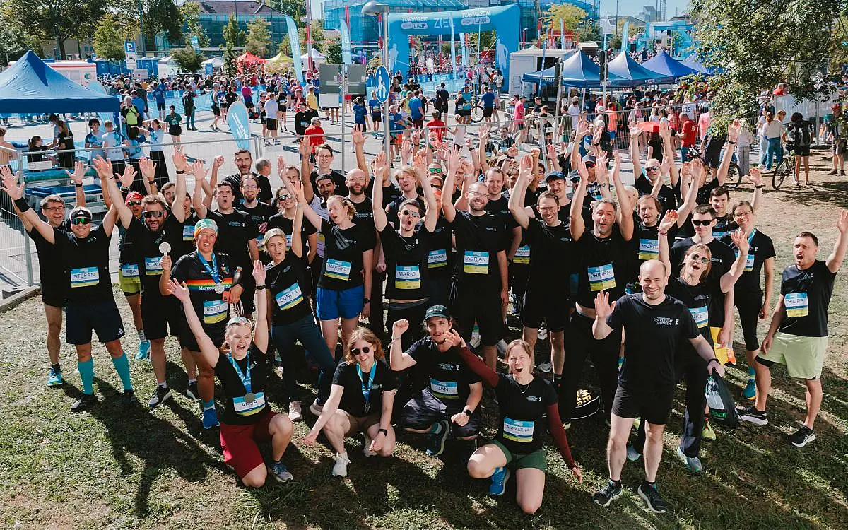 Eine Gruppe jubelnder Menschen in Sportkleidung mit schwarzen T-Shirts