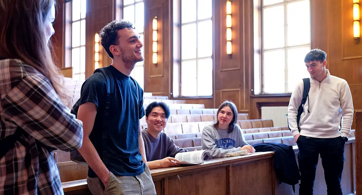 Studierende stehen entspannt im Hörsaal und diskutieren
