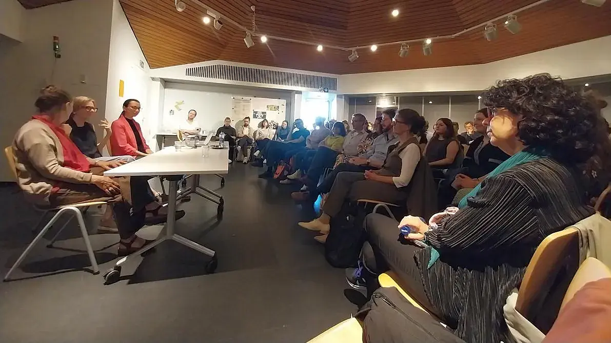 Pult mit drei Personen in vollem Hörsaal