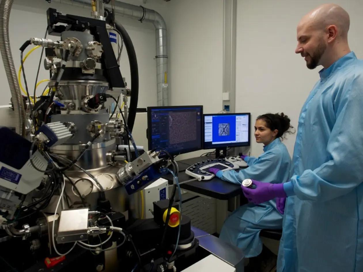 Doktorandin Inci Can (sitzend) und Dr. Ronny Löffler, wissenschaftlicher Mitarbeiter, am Helium-Ionenmikroskop des Center for Light-Matter Interaction, Sensors & Analytics (LISA+) 