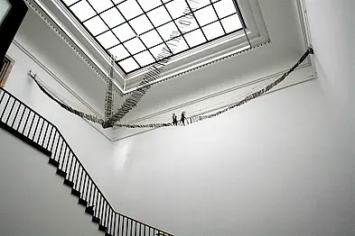 Fotografie des Werks "Emigrants 2011", das sich in einem lichtdurchfluteten Treppenhaus befindet