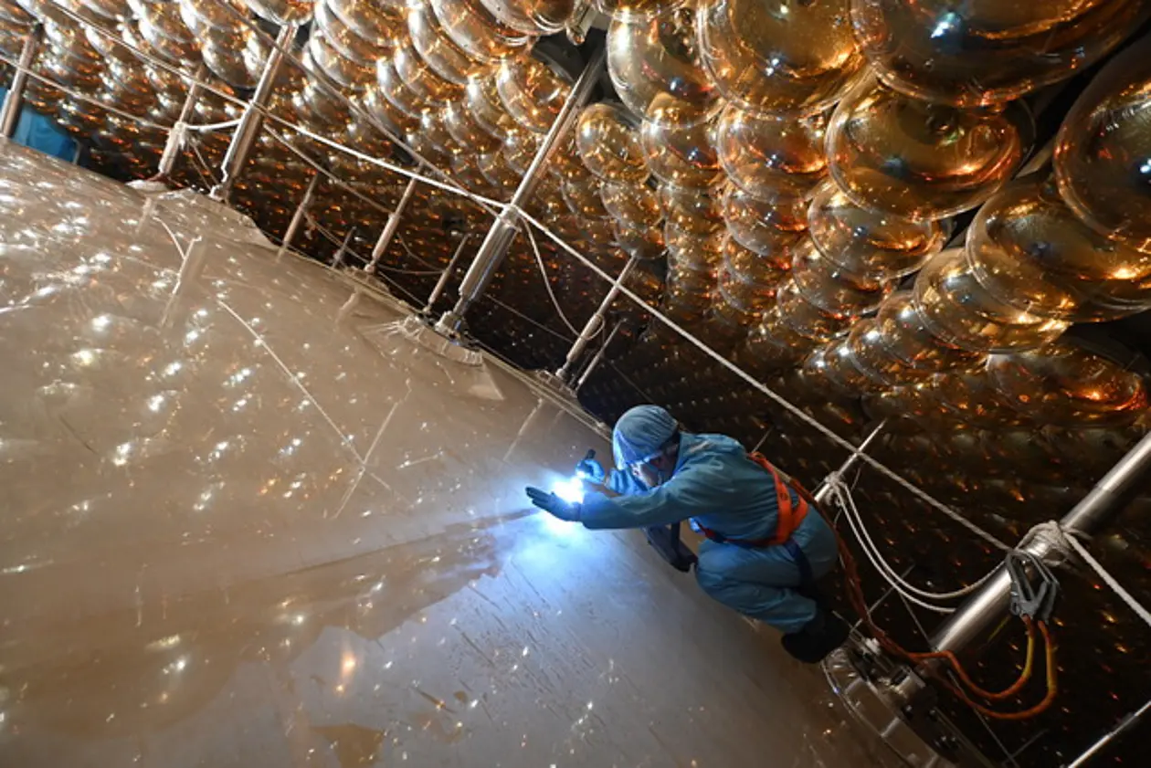 Photo of part of the white spherical detector and a person in protective clothes