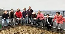 The research group of Vision and Cognition sits outside on a bannister in front of mountains