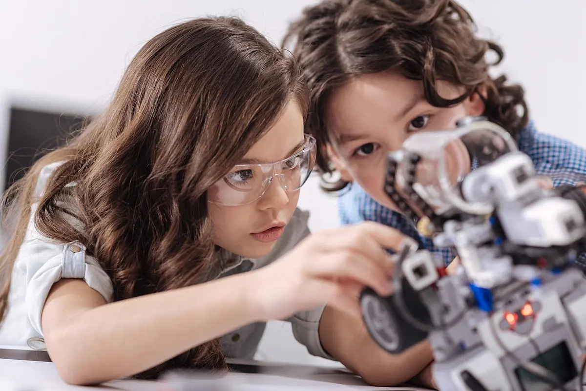 Zwei Kinder untersuchen einen kleinen Roboter