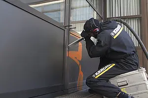 Mit dem Partikelstrahlverfahren werden Graffiti vom Betonsockel des Neuphilologikums entfernt. Fotos: Friedhelm Albrecht