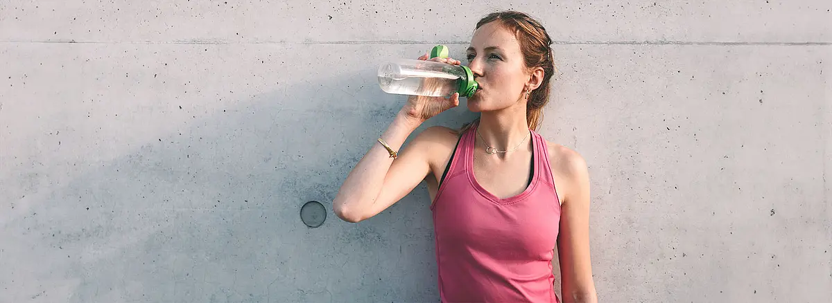 Sportlerin trinkt aus einer Wasserflasche