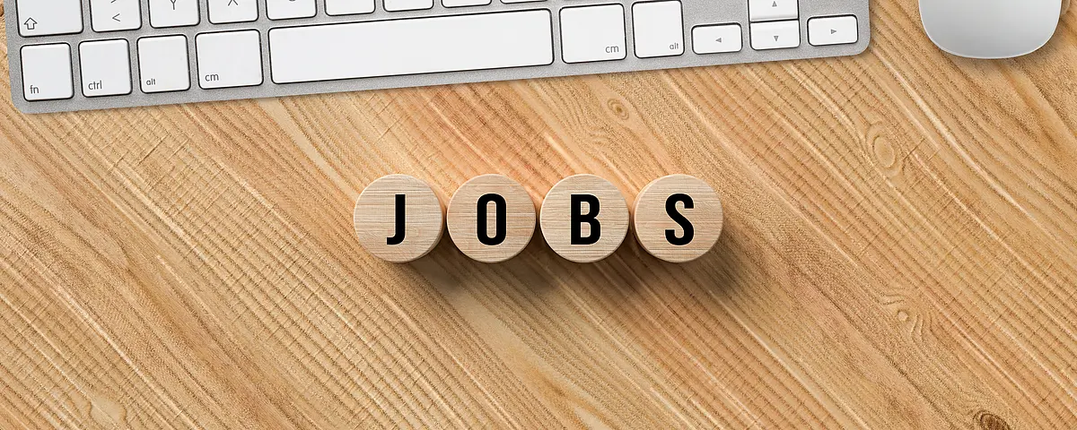 Wooden letters spelling the word jobs lay on a desk in front of a keyboard