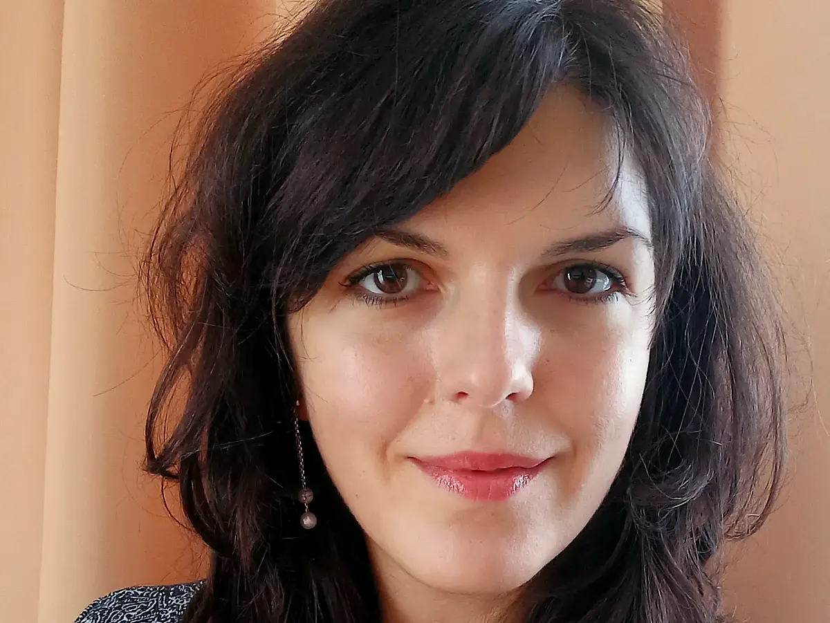 A woman in her early 30s with dark shoulder length hair