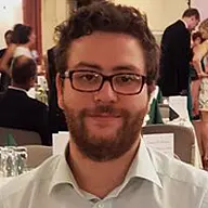 Matthias Baumann lächelt in die Kamera. Hinter ihm stehen mehrere Personen.