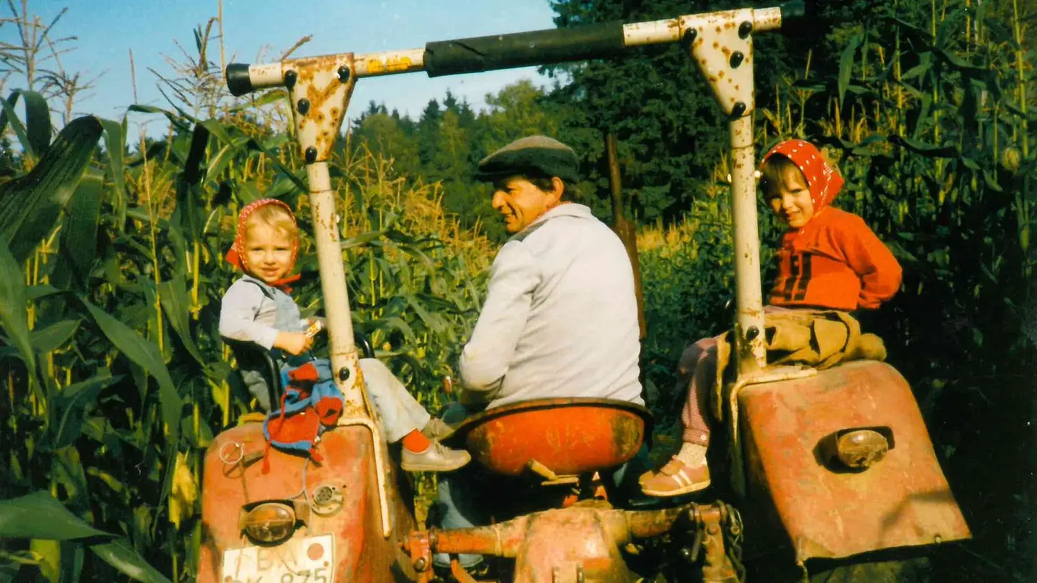 Traktor mit Fahrer und je einem Mädchen auf beiden Seiten.