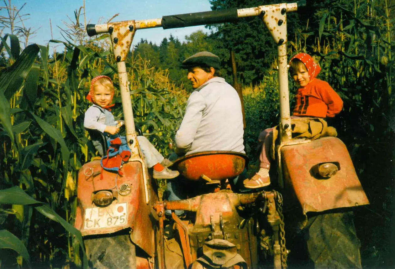 Traktor mit Fahrer und je einem Mädchen auf beiden Seiten.
