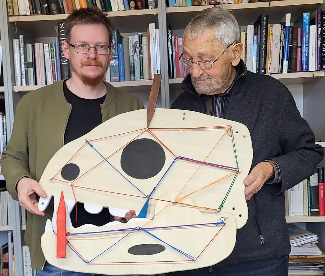 PD Dr. Ingmar Werneburg (links) und Prof. Dr. Holger Preuschoft (rechts) mit einem Modell eines Wirbeltierschädels, den verschiedene Spannungsverläufe durch farbige Fäden gekennzeichnet sind.