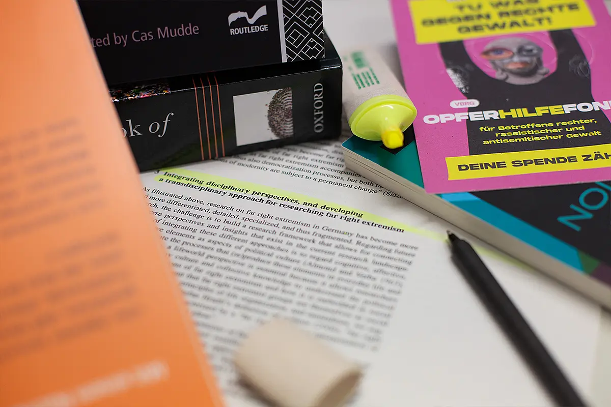 Das Bild zeigt einen Tisch mit Büchern, Stiften und einem Text.