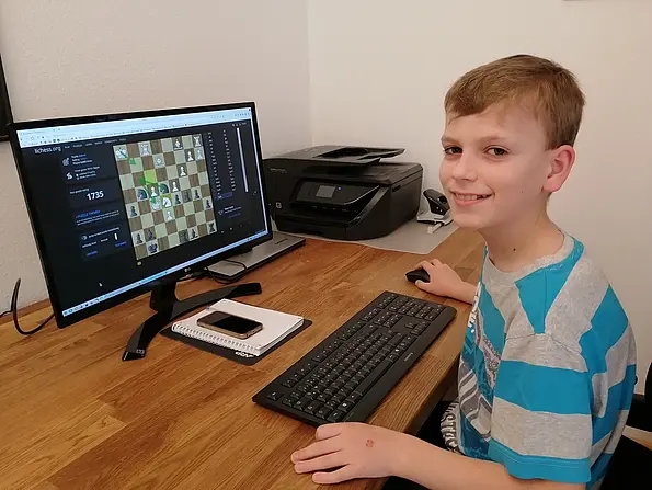 Foto mit Hannes, dem Sieger des Online-Schachturniers, am Computer sitzend.
