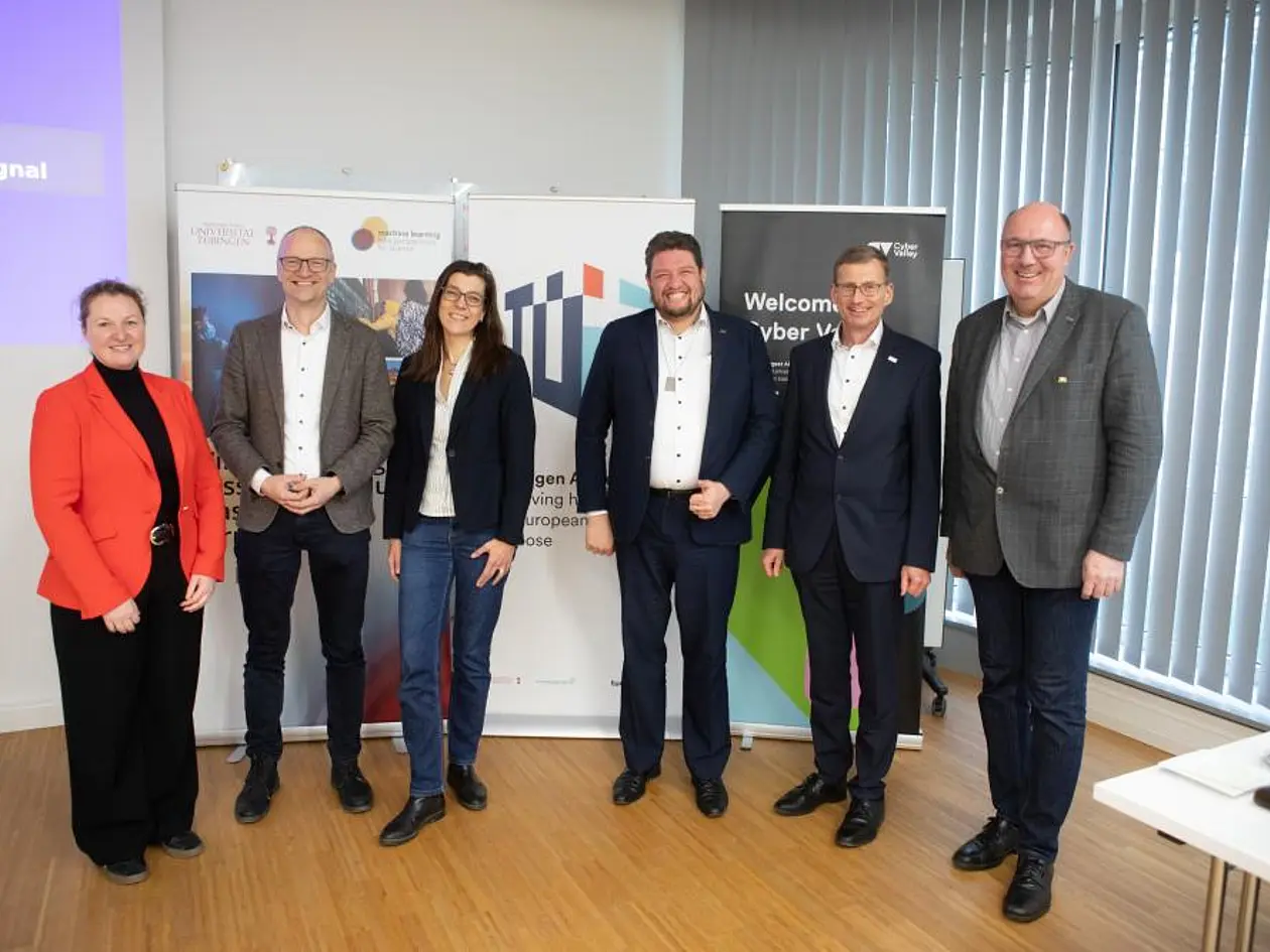 Gruppenfoto mit Professorin Dr. Katja Schenke-Layland, des. Prorektorin, Prorektor Professor Dr. Samuel Wagner, Dr. Susanne Aschoff, Michael Joukov, Kanzler Dr. Andreas Rothfuß und Norbert Knopf (von links nach rechts). Im Hintergrund Roll-Ups von Exzellenzcluster Machine Learning, Tübingen AI Center und Cyber Valley.