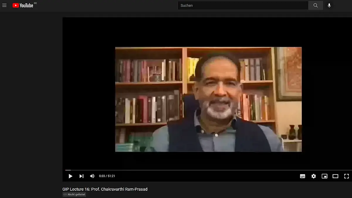 A man with dark hair and white-gray beard speaks into a webcam