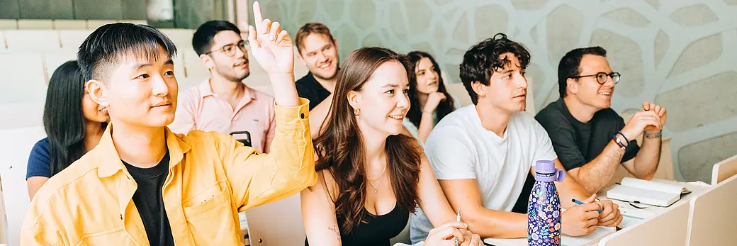 Acht Studierende sitzen in einem Seminarraum und haben Spaß am Studium