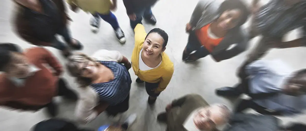 Eine Gruppe Menschen von oben, im Fokus eine nach oben blickende Frau