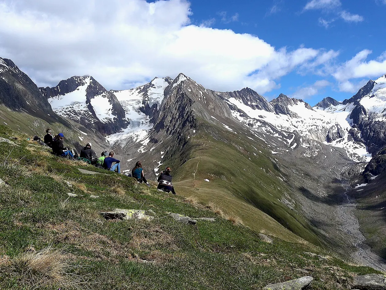In the picture you can see the Alpes and the participants of the excursion sitting on the groundAuf dem Bild sieht man das Gebrige der Alpen und die Exkursionsteilnehmen, die dort auf der Wiese sitzen