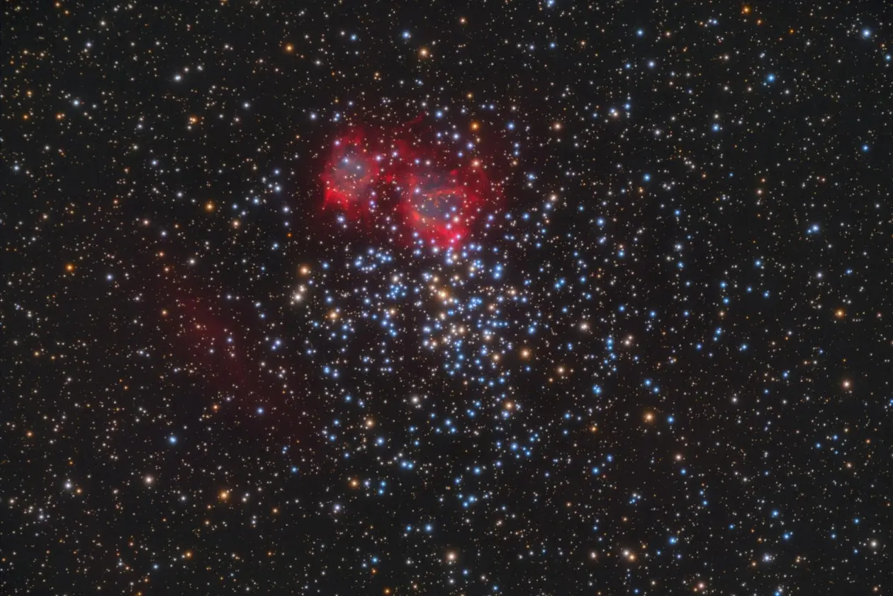 Cluster of bright dots with surrounding red nebula against black background