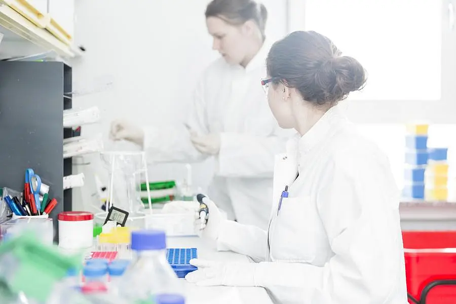 Zwei Wissenschaftlerinnen in Laborkitteln bei der Vorbereitung von Proben
