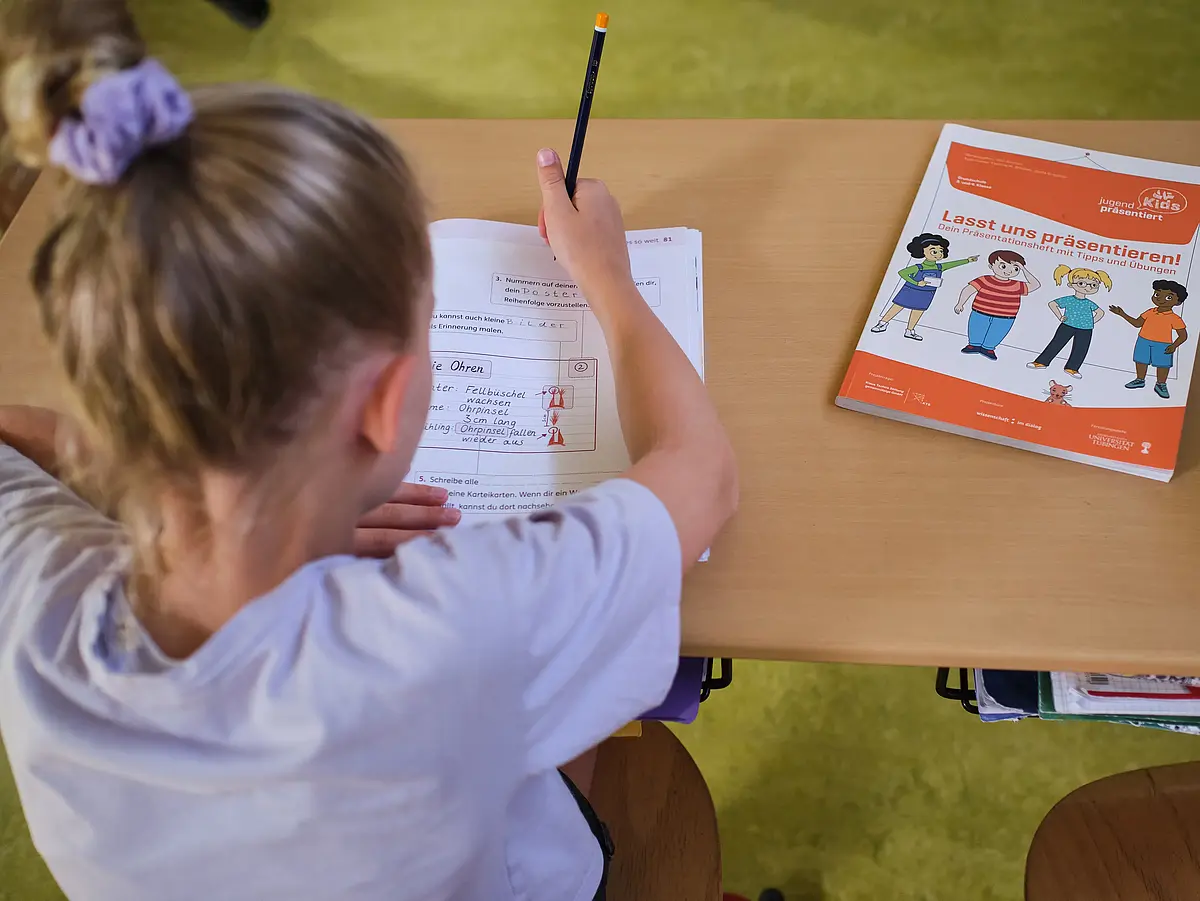 Ein Kind schreibt in ein Arbeitsheft